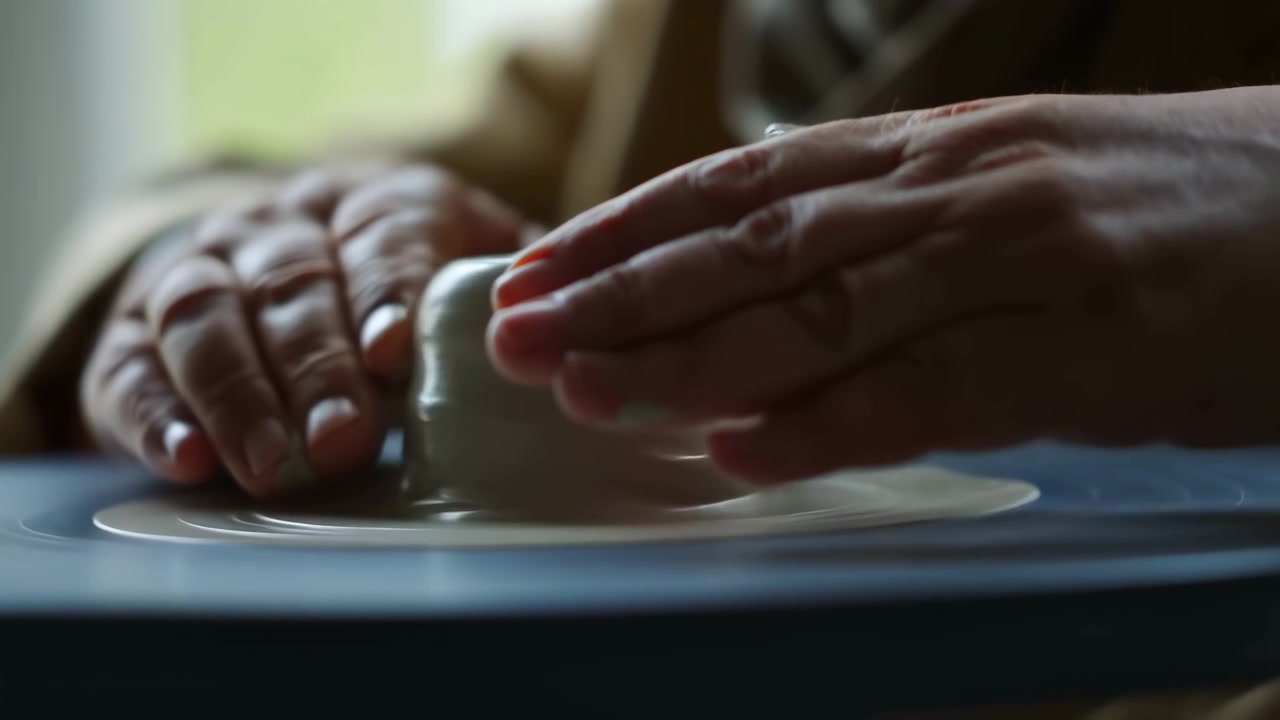 Close-up of adult hands gently holding a ceramic cup on a saucer in soft warm indoor light, with a blurred background and a calm, cozy mood