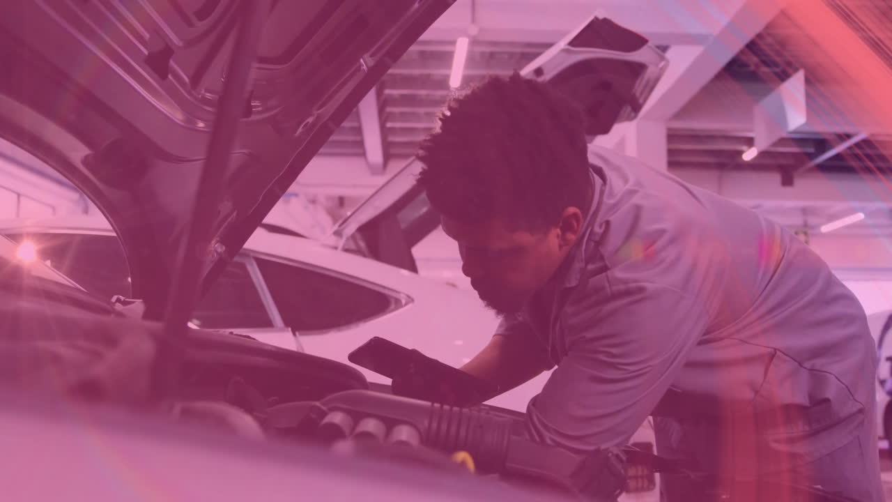 Male mechanic holding smartphone leaning over car engine in auto shop, showing animated overlays