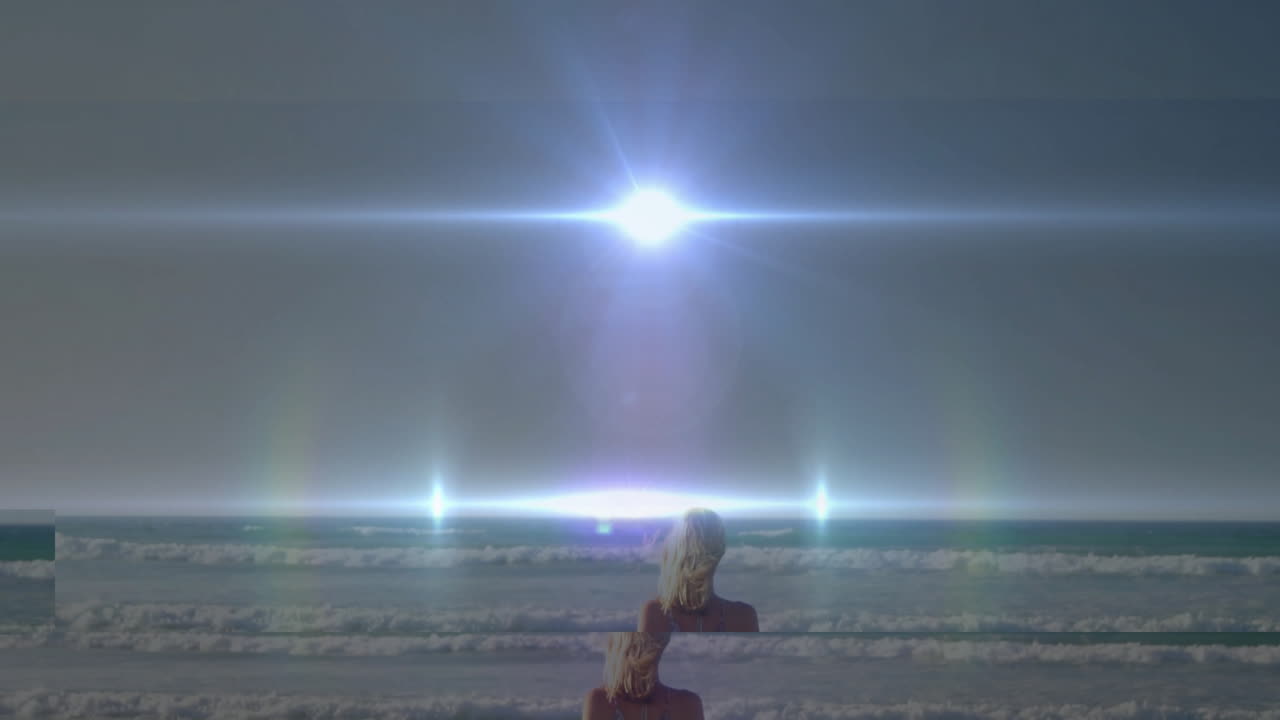 Standing on beach, person watching bright light shining over ocean waves