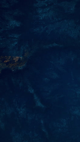 aerial view of dark blue ocean water with rocks