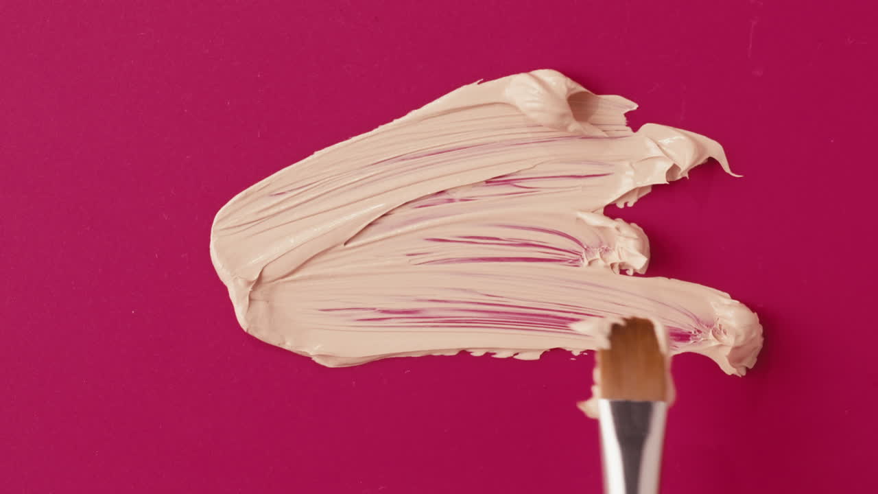Foundation swatch with brush on pink background