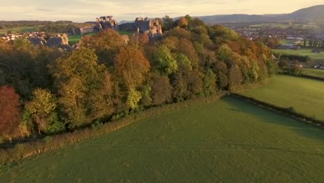 Panorámica-Hacia-Arriba-Revelando-Las-Ruinas-Del-Castillo-Sentado-En-La-Cima-De-Una-Colina-Sobre-El-Pueblo-En-La-Ciudad-Galesa