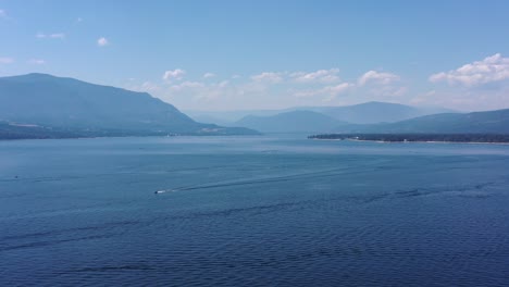 distant journey: boat gliding across shuswap lake's serene waters