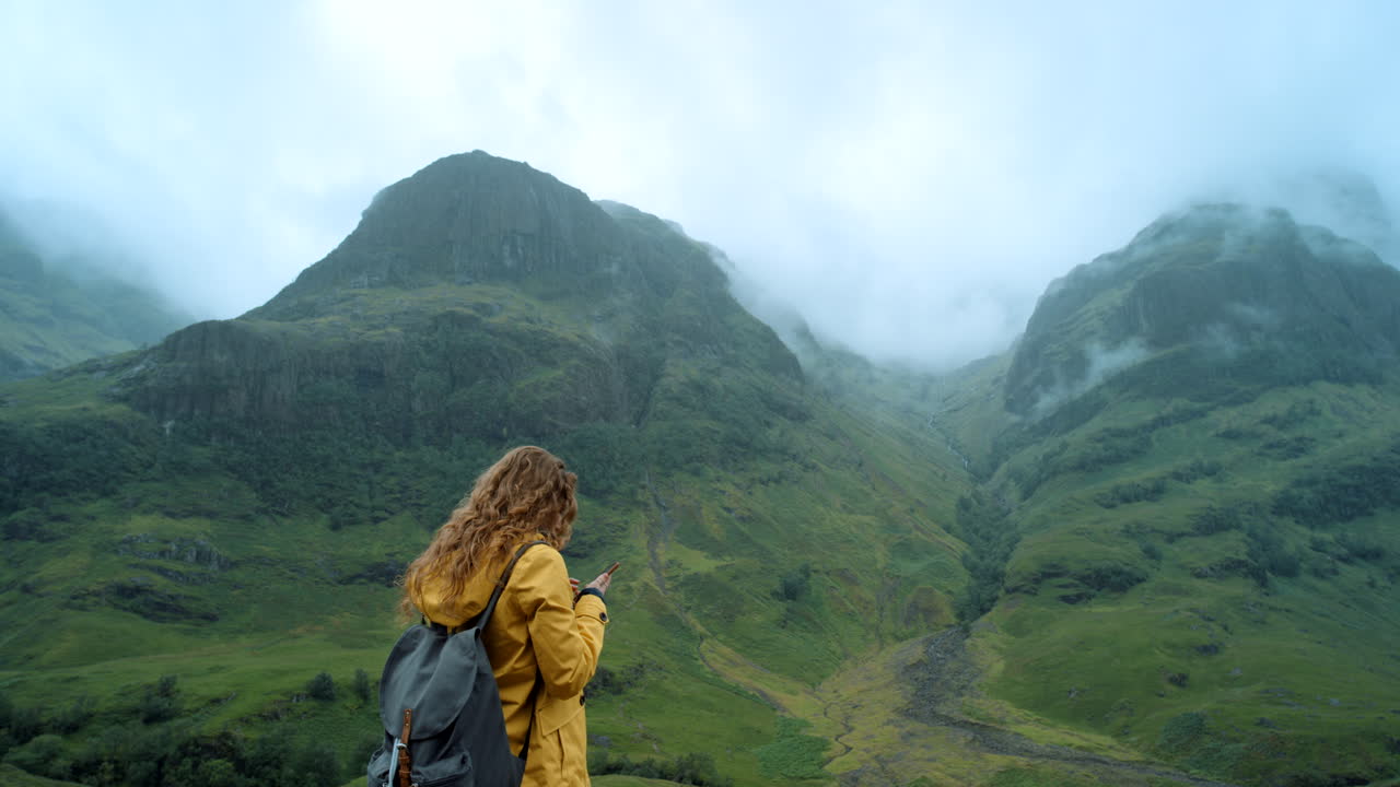 Woman taking photo of Scottish Highlands landscape