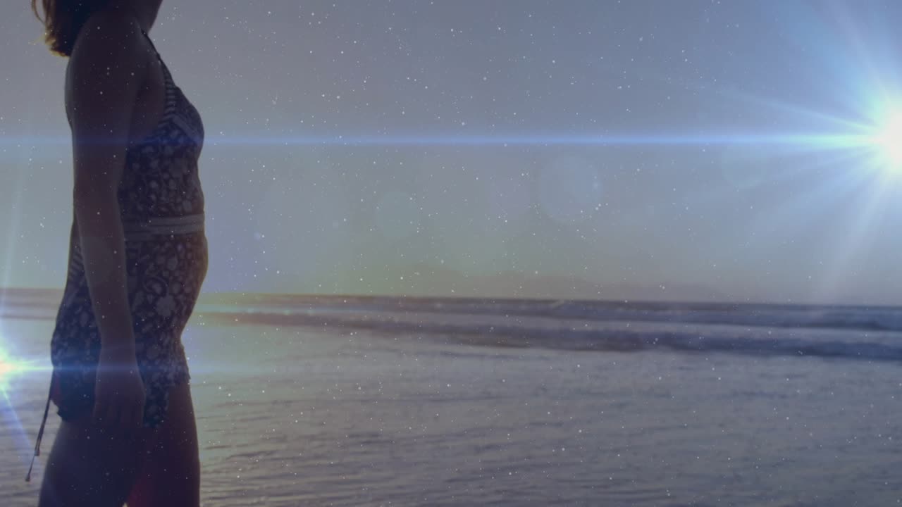 Stepping into water and walking shoreline woman generating sunset travel visuals with lens flares