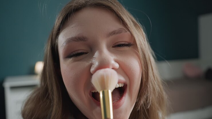 White teenage girl brushing nose playfully, closeup bedroom clip showing giggles and spontaneous laughter, cheek tickle with makeup brush, upbeat social media vibe, candid expressive shots, lamp