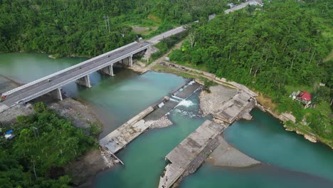 Aerial pullback of Pajo River and water flowing through dam surrounded by a lush tropical island setting. Santo Domingo, Virac, Catanduanes
