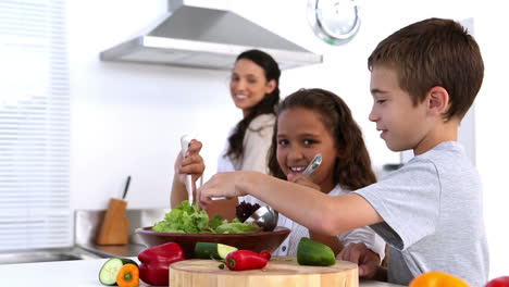 siblings making salad together with mother watching