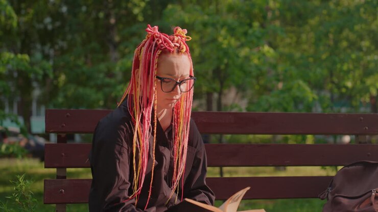 park scene with reading woman, woman with braided pink hair studies peacefully, serene woman on park bench immersed in reading, closeup of woman with pink braids quietly reading on park bench