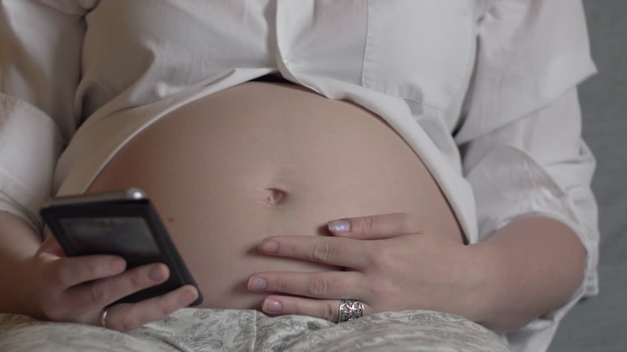 Donna incinta che si rilassa con uno smartphone