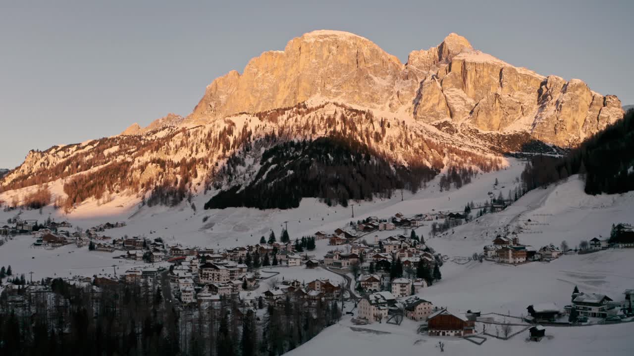 toma cinematográfica de un dron descendente de un pueblo de montaña en la base de una gran luz del amanecer de montaña