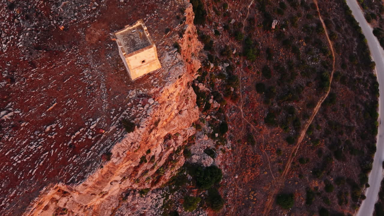 Aerial Sicilian cliffs at sunset with a lone historic tower, peaceful vibe