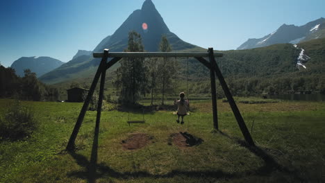 a girl swinging in a beautiful valley surrounded by mountains