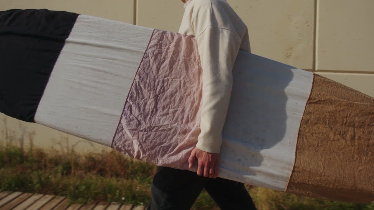 Surfer man walking to the beach at sunset preparing for surfing training and search for waves in Barcelona, spain, water, ocean exercise in sea with board, athletic male holiday or travel in vacation