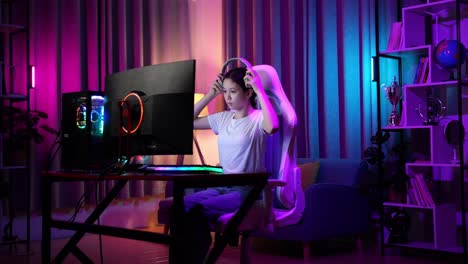 asian teen girl gamer wearing head phones and start play video game on computer