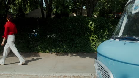 woman walking with coffee on the street near a vintage van