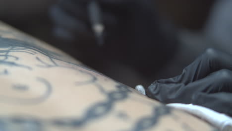 tatuador profesional usando palo y mano y tinta negra
