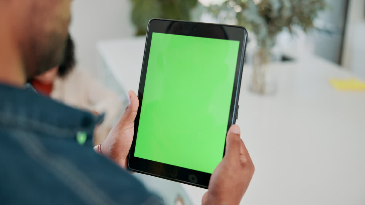 Man holding a tablet with a green screen