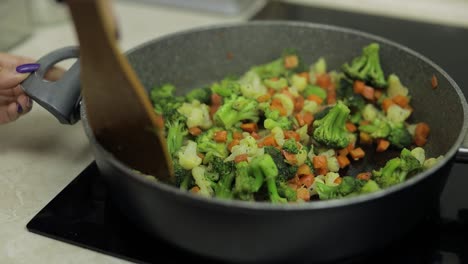 woman cooking vegetables in a pan