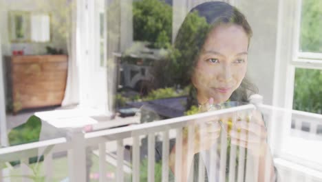 happy asian woman drinking tea and looking through window, in slow motion