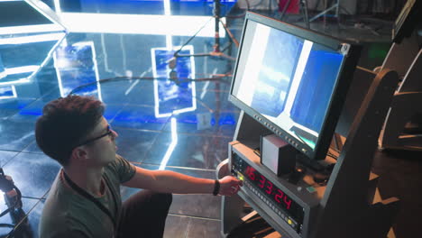 person adjusting controls on video equipment in tv studio, focused on screen displaying broadcast setup. timer on control panel shows time, with cables and equipment visible in background