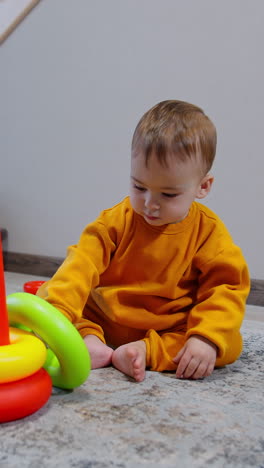 sweet kid playing with a toy pyramid sitting in the room. adorable child notices camera and joyfully crawls up to it. vertical video