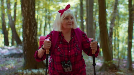 abuela turista anciana involucrada en el deporte de la caminata nórdica caminata con mochilas, palos de trekking
