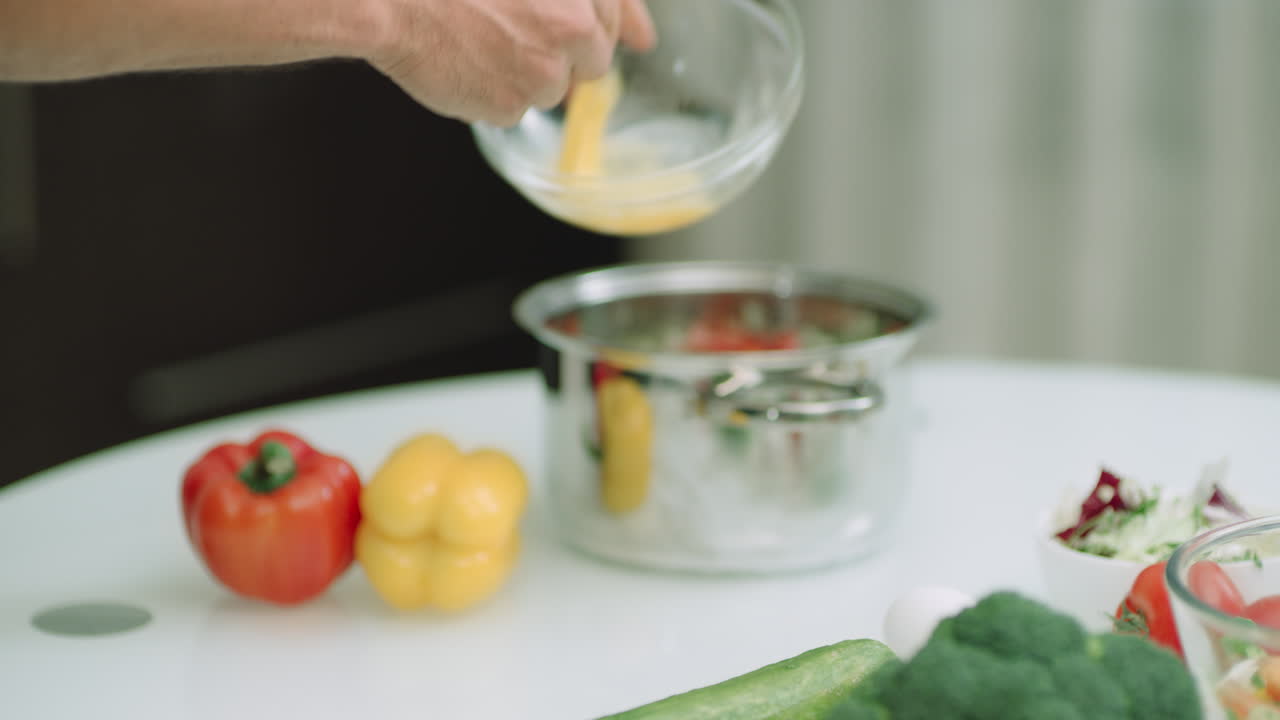 Closeup man hands adding whisked eggs into pot. Man hands cooking ingredients