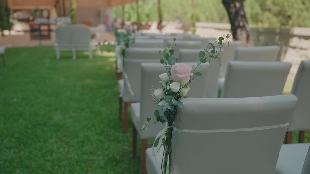 Disposizione dei posti a sedere per la cerimonia di matrimonio con composizioni floreali sulle sedie all'aperto