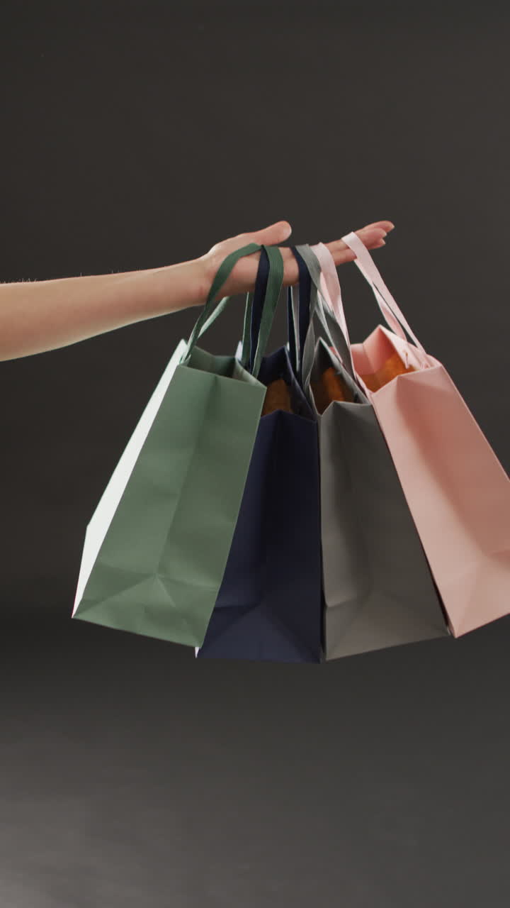 회색 배경에 쇼핑 가방과 함께 손의 수직 비디오