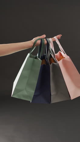 video vertical de la mano con bolsas de compras en fondo gris