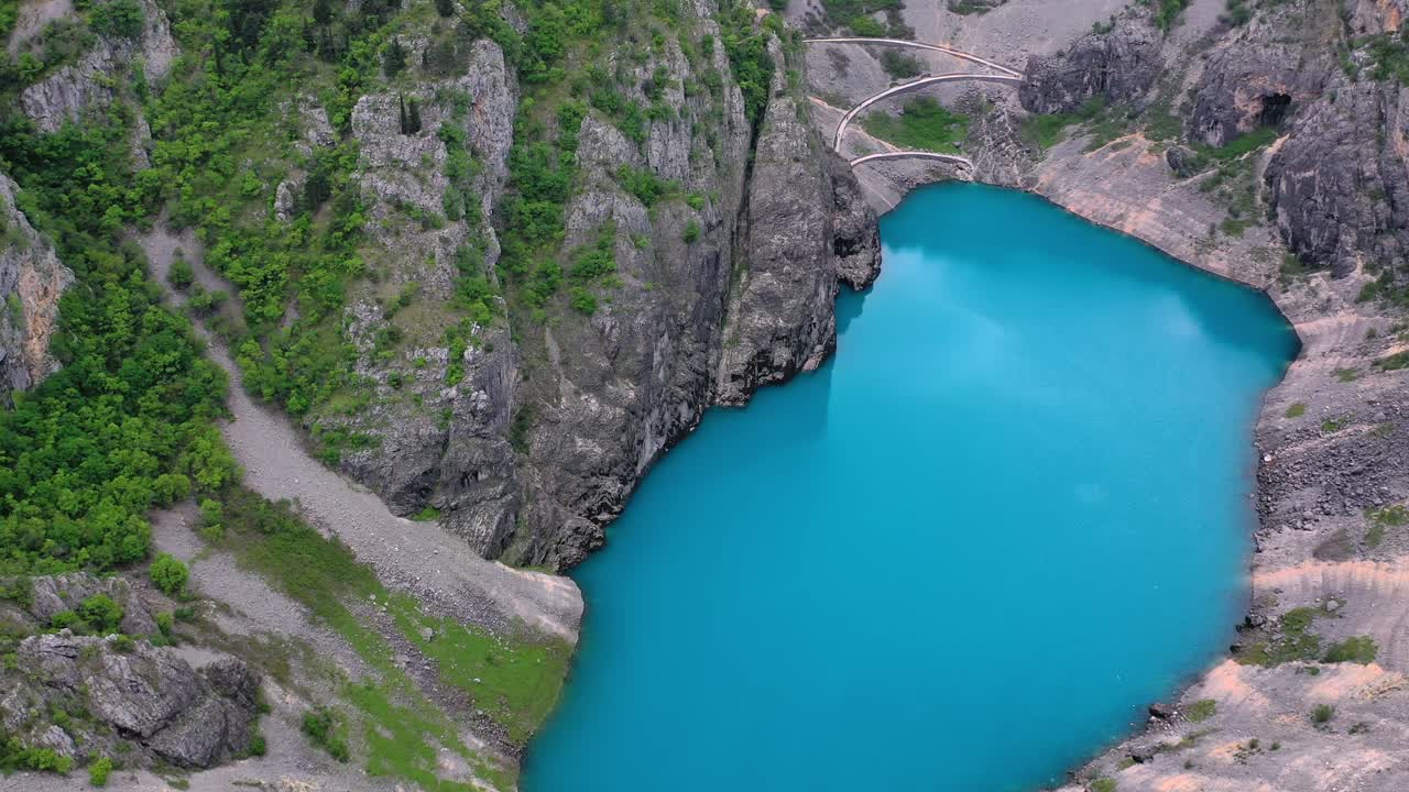 Medium wide angle left side panning drone shot of blue lake and surrounding hills in Imotski during the day