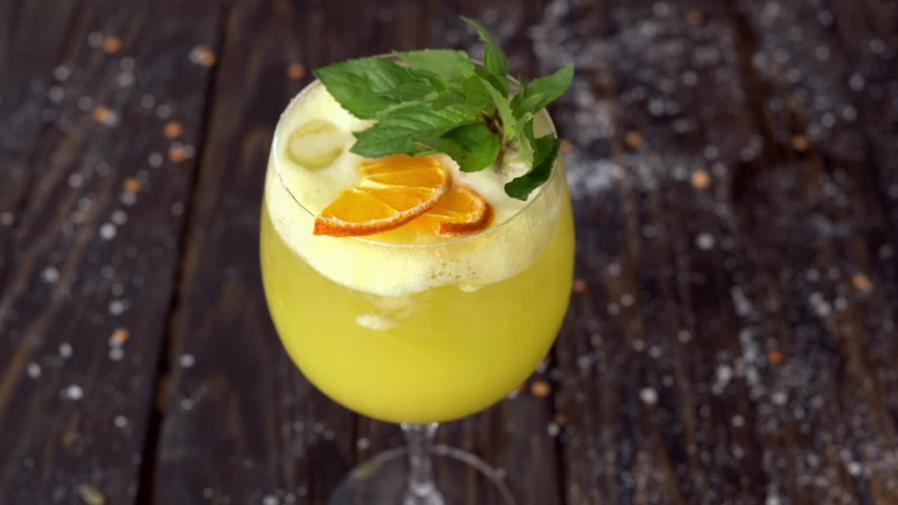 Un bicchiere di limonata gialla con menta su una superficie di legno