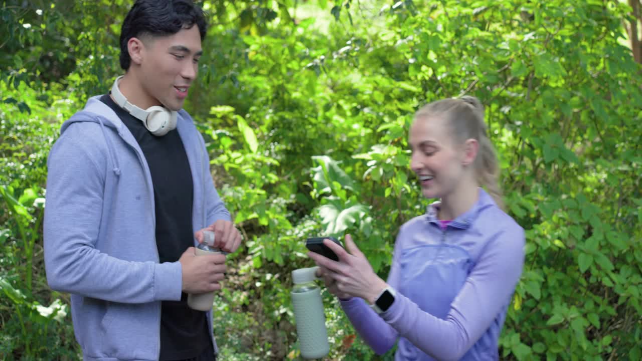 Amigos diversos jadeando después de correr, compartiendo botellas, tomándose una selfie y bebiendo en el sendero.
