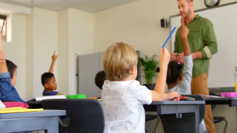 multi-ethnic schoolkids raising hands while sitting at desk in a classroom at school 4k