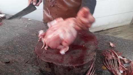 men cutting raw chicken meat at the outdoor workshop in india