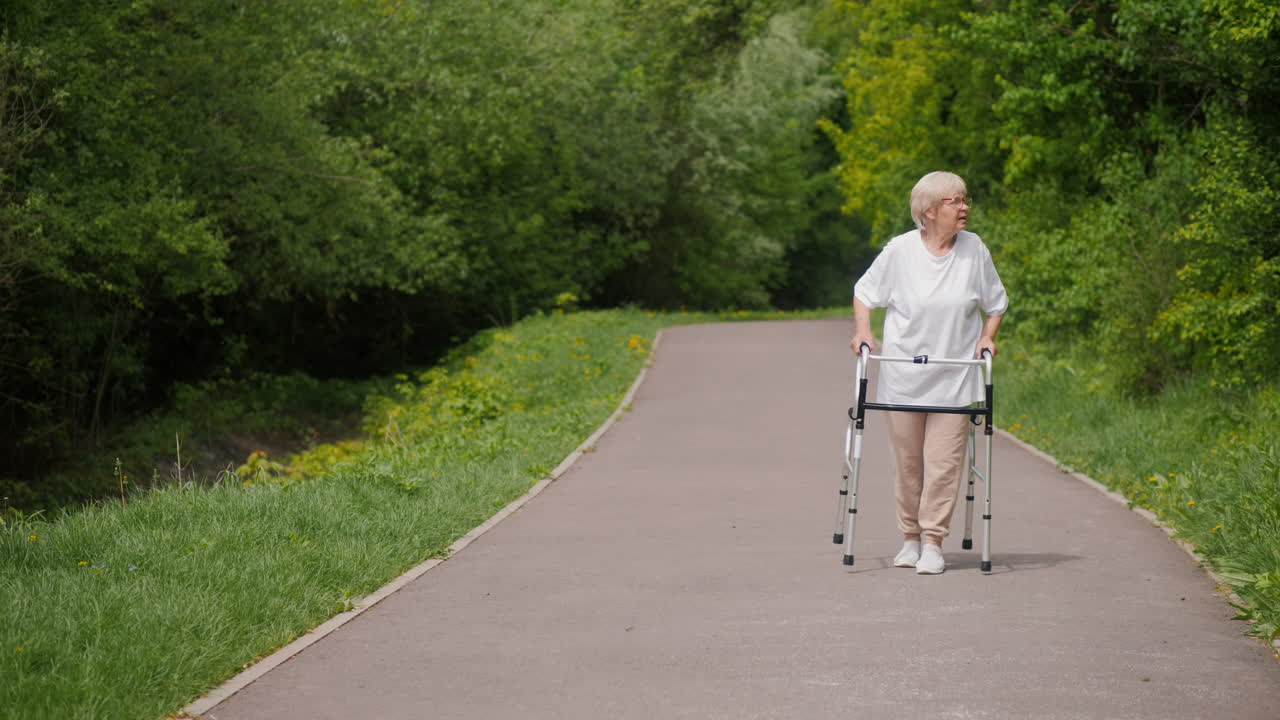 Eldre kvinne spaserer i parken med rullator