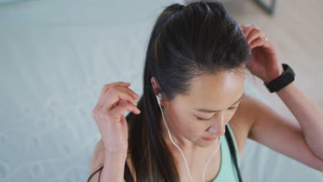 Retrato-De-Una-Mujer-Asiática-Usando-Auriculares,-Preparándose-Para-Hacer-Ejercicio,-Atando-El-Cabello