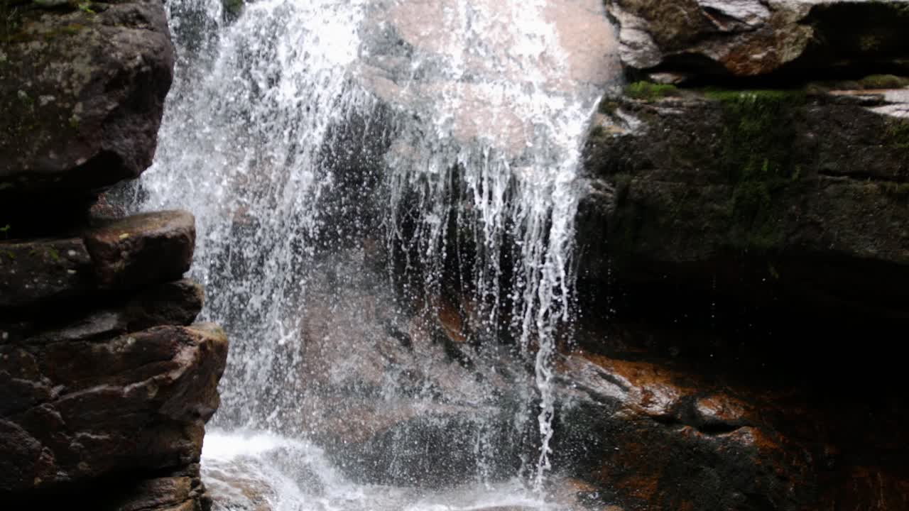 una cascada desciende por varios salientes de piedra y desemboca en un arroyo tranquilo dentro de un desfiladero