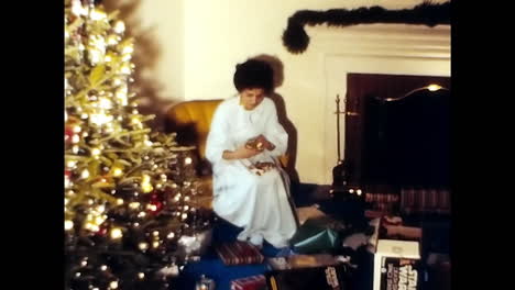 woman standing in front of christmas tree. circa usa - 1970s: a woman stands in front of a decorated christmas tree in a 1970s video from the usa.