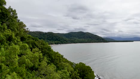 aerial view of lush rainforest and winding coastal road in port douglas, australia, under overcast skies