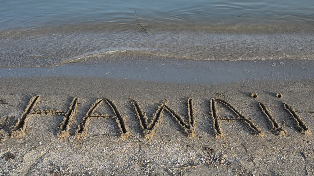 Inskriptionen 'Hawaii' gjord på en vacker strand. Inskription på sand, stranden.