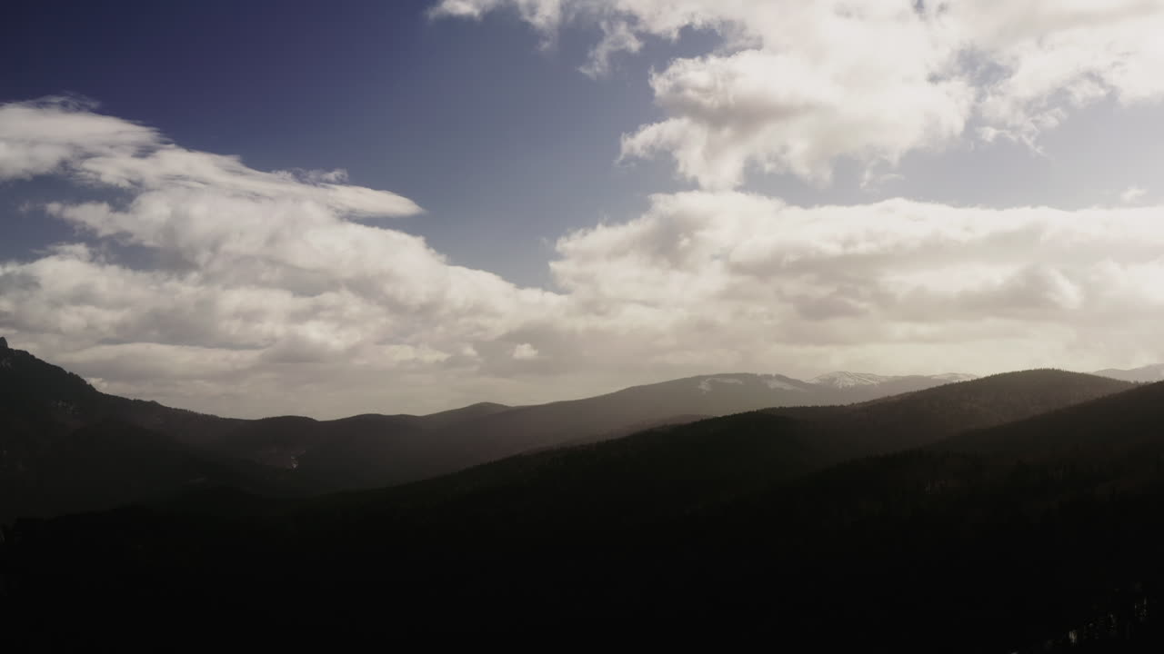 변덕스러운 구름이 있는 실루엣 산의 공중 드론 샷
