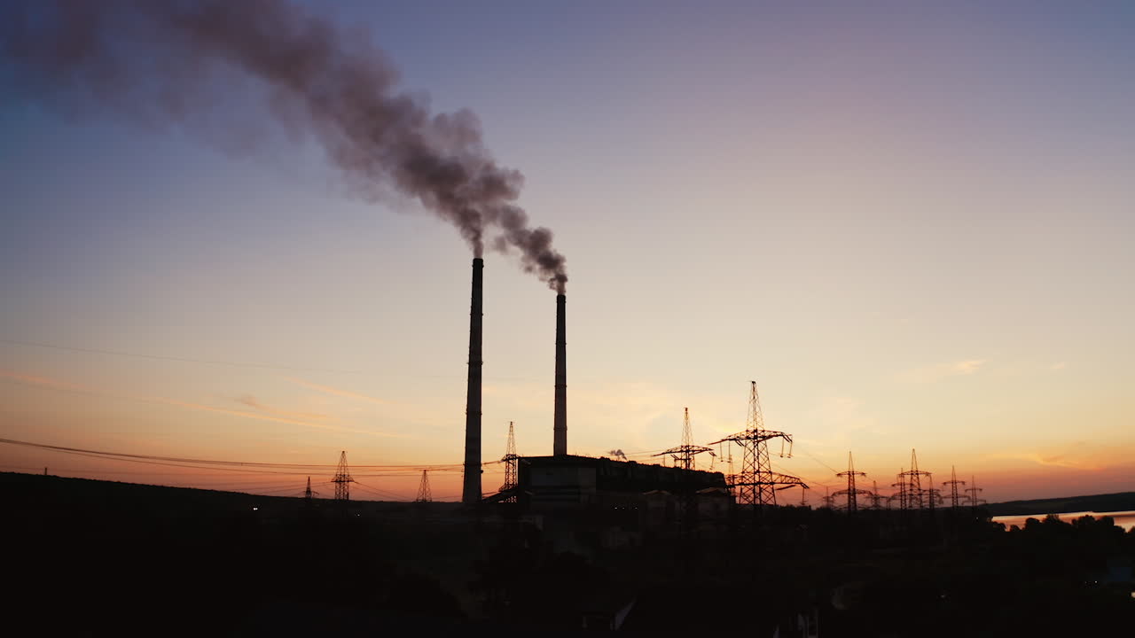 Factory tubes on the sunset background. Smoke from the pipes. Pollution concept. Video from the air.