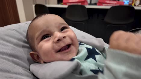 Happy,-laughing-4-month-infant-boy-playful-interaction-with-out-of-shot-parent-CLOSE-UP