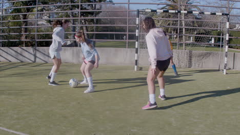 four teenagers girls playing soccer at outdoors and scores