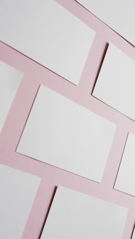 vertical video of white business cards arranged on pink background, copy space, slow motion
