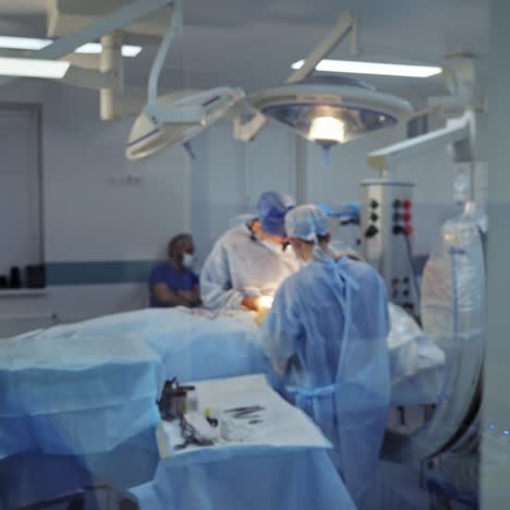 modern operating room in the hospital. view through the window into the surgical room with operating process. camera moves forward.