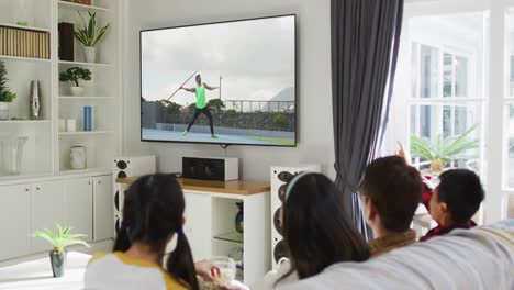 행복 한 가족 이 집 에서 함께 앉아서 tv 에서 육상 자벨린 대회 를 시청 하고 있다