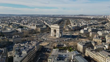 Triumphal-arch-or-Arc-de-Triomphe-and-car-traffic-on-roundabout-with-Paris-cityscape,-France